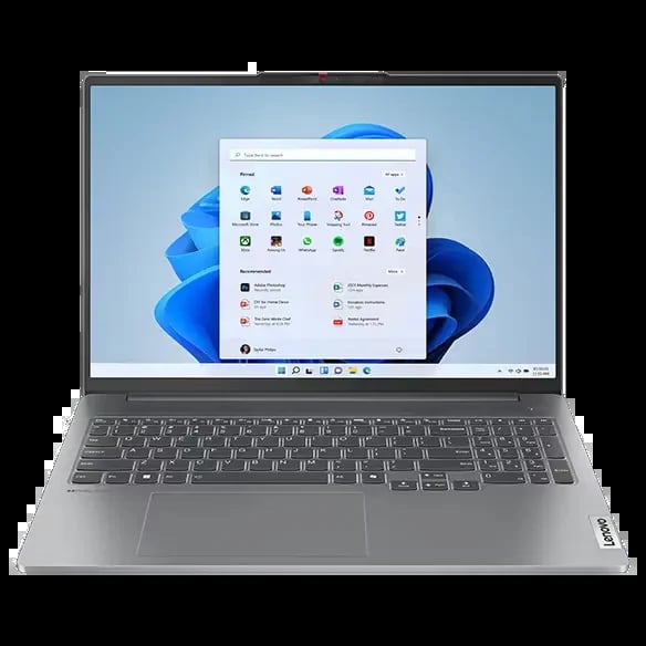 Silver laptop displaying Windows 11 start menu with app icons on blue abstract background wallpaper