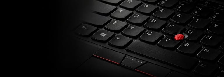Close-up of a black laptop keyboard with a red trackpoint button highlighted in the center