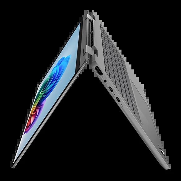 Silver laptop opened in tent position showing colorful feather wallpaper on screen and keyboard base